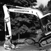 A digger working hard to hold back the hillside threatening the Lustleigh Village Hall