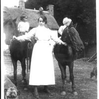 Young woman leading two children on ponies