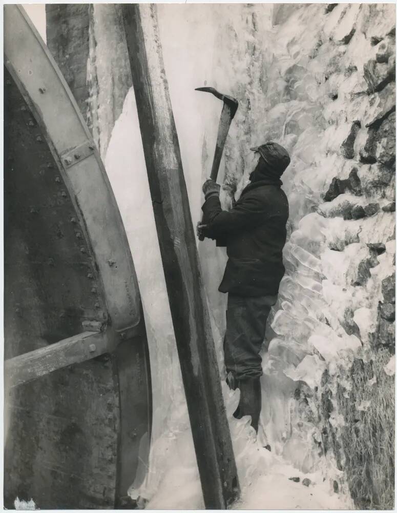 Clay worker trying to free up a frozen water wheel